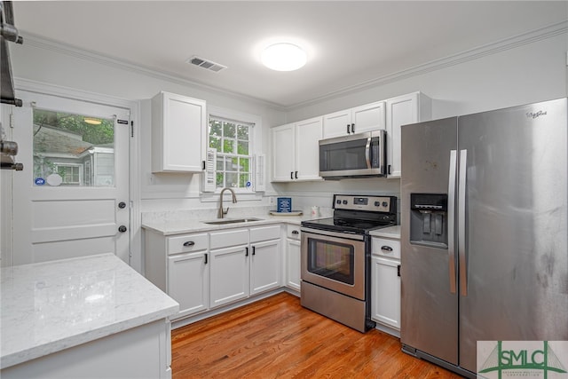 kitchen with white cabinets, appliances with stainless steel finishes, a sink, visible vents, and ornamental molding