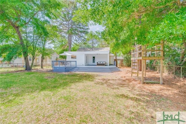 exterior space with fence, a wooden deck, and a yard