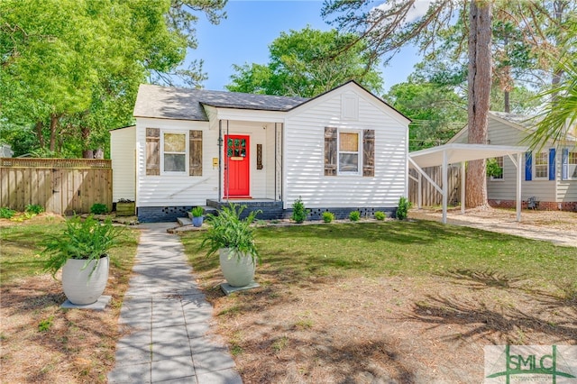 bungalow-style house with a front yard, fence, and a detached carport