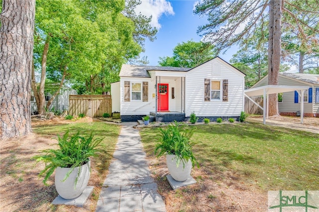 bungalow-style house with fence, a detached carport, and a front lawn