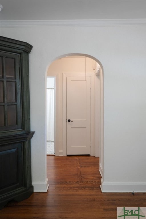 hall with arched walkways, baseboards, ornamental molding, and wood finished floors