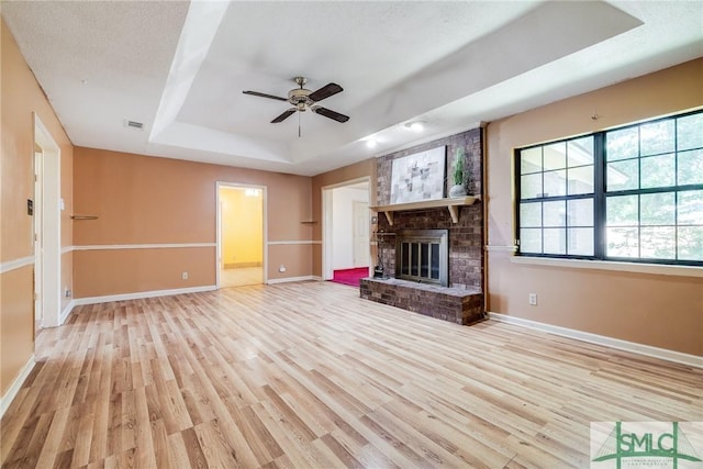 unfurnished living room with a raised ceiling, baseboards, a ceiling fan, and wood finished floors