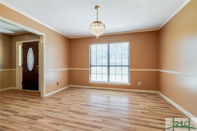 interior space featuring light wood-style floors, baseboards, crown molding, and an inviting chandelier