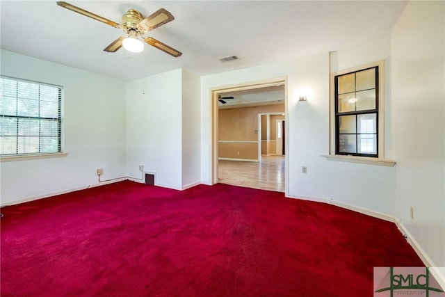 carpeted empty room featuring visible vents, baseboards, and ceiling fan