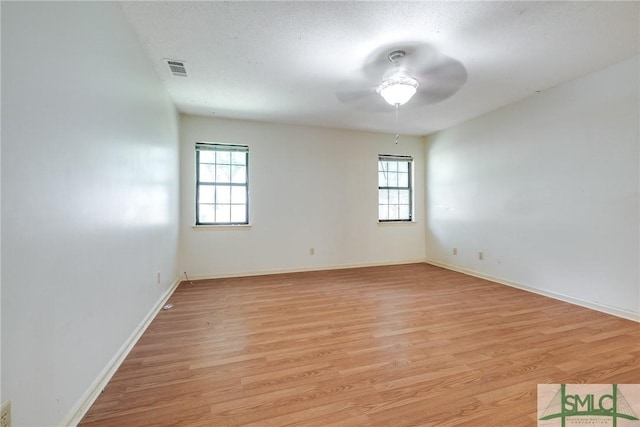 spare room with ceiling fan, plenty of natural light, light wood-style flooring, and visible vents