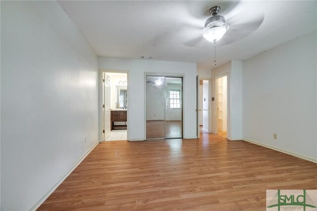 unfurnished bedroom featuring light wood-type flooring, baseboards, ensuite bathroom, and visible vents
