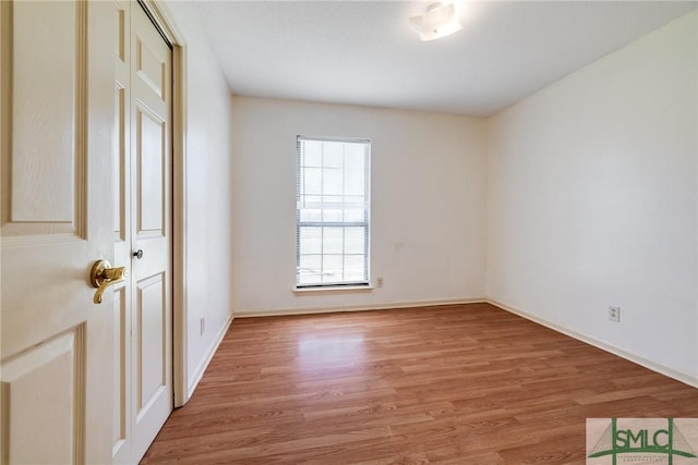 spare room with baseboards and light wood-type flooring