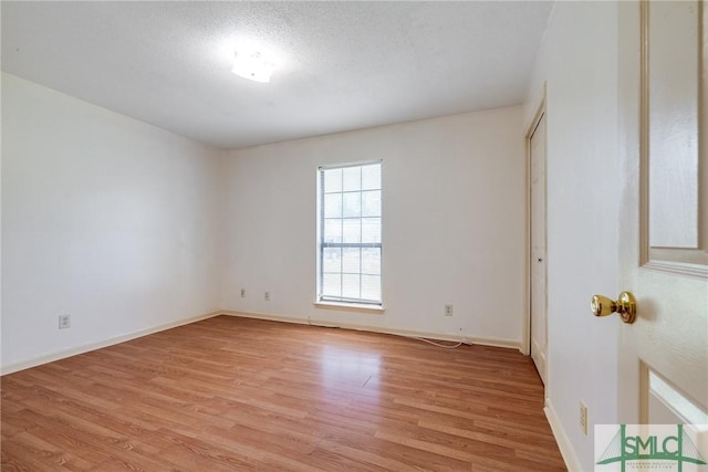 spare room featuring baseboards and light wood finished floors