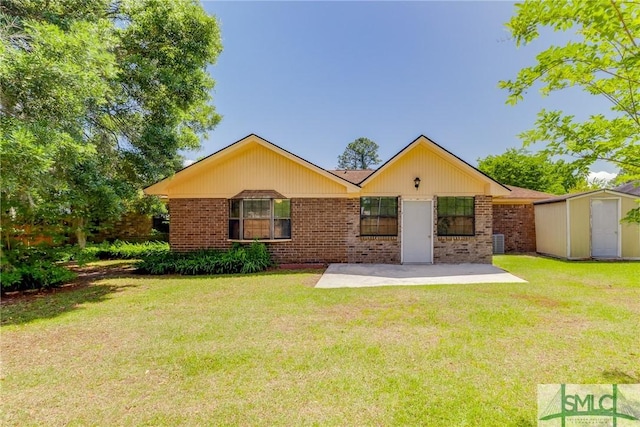 view of front of property with a storage shed, brick siding, a patio, and a front yard