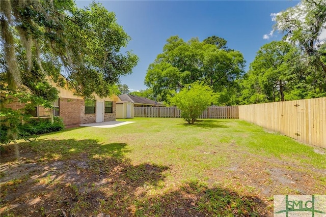 view of yard with a storage unit, a fenced backyard, an outbuilding, and a patio