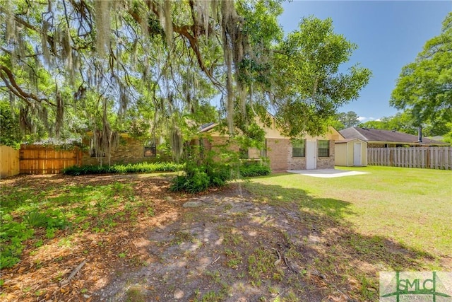 view of yard featuring a fenced backyard, a storage unit, and an outdoor structure