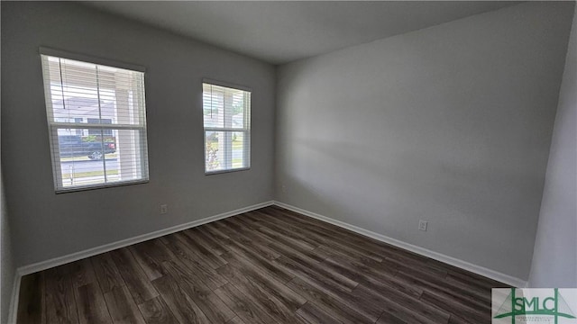unfurnished room featuring baseboards and dark wood finished floors