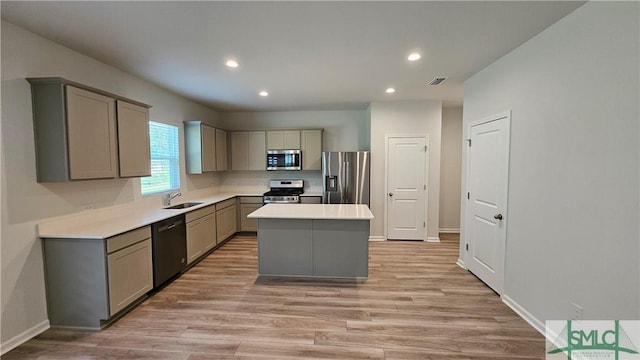 kitchen featuring recessed lighting, light wood-type flooring, gray cabinets, a center island, and stainless steel appliances