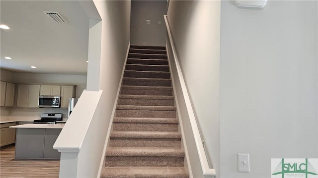 stairway featuring recessed lighting, visible vents, and wood finished floors
