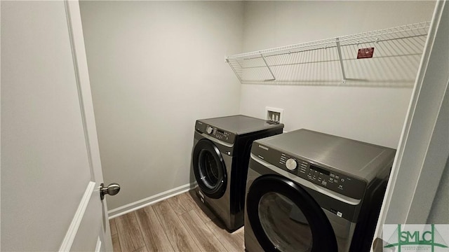 washroom with baseboards, laundry area, light wood finished floors, and washer and dryer