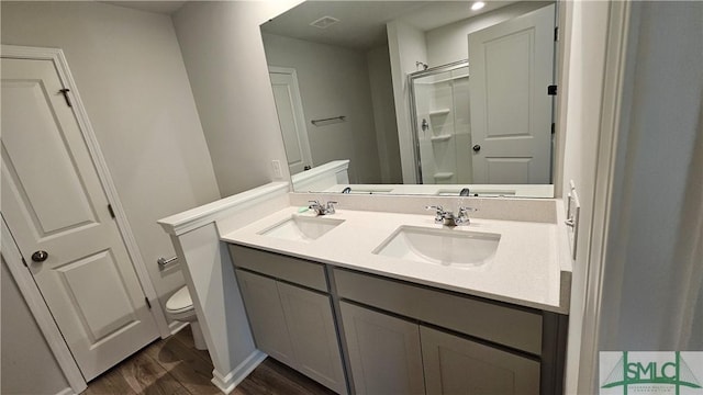 bathroom with a sink, a shower stall, toilet, and wood finished floors