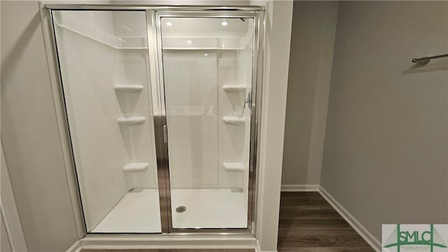 bathroom with wood finished floors, baseboards, and a stall shower