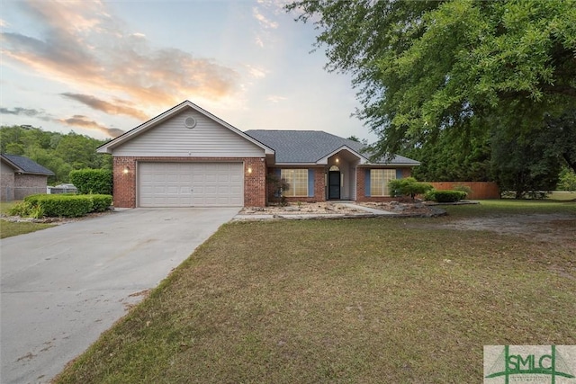 single story home featuring a lawn, brick siding, an attached garage, and driveway