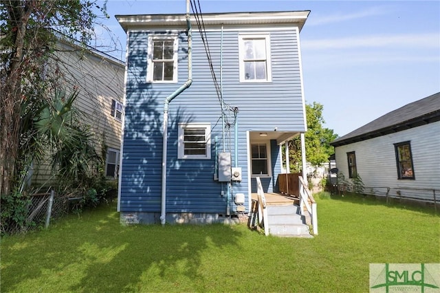 rear view of house with a lawn and fence