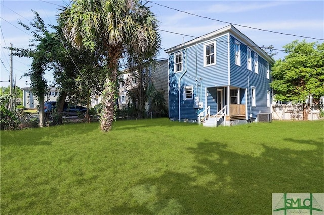 rear view of property featuring central air condition unit and a yard