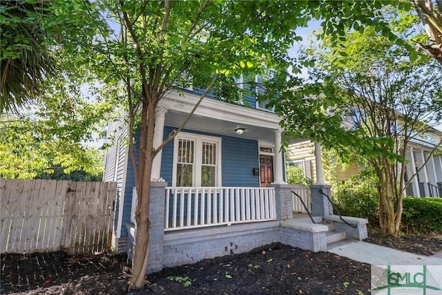shotgun-style home featuring a porch and fence