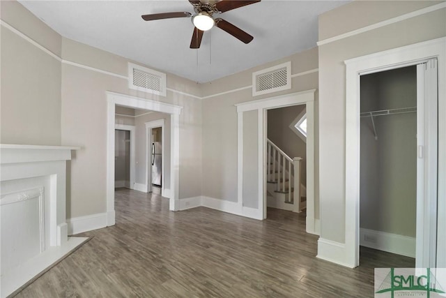 unfurnished living room with a ceiling fan, visible vents, and wood finished floors