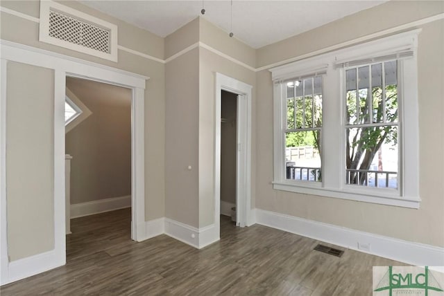 unfurnished room with baseboards, wood finished floors, and visible vents