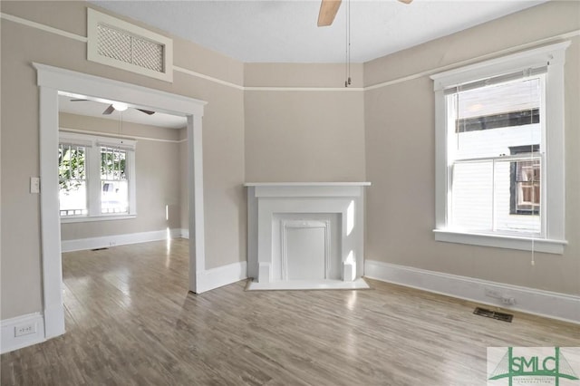 unfurnished living room with baseboards, a ceiling fan, wood finished floors, and visible vents