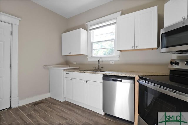 kitchen with white cabinets, a sink, stainless steel appliances, baseboards, and dark wood-type flooring