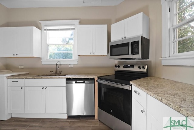 kitchen with a sink, wood finish floors, white cabinets, and stainless steel appliances