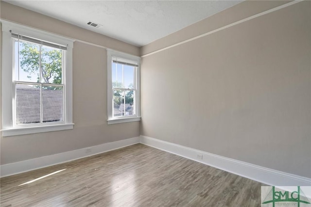 unfurnished room with visible vents, baseboards, and wood finished floors