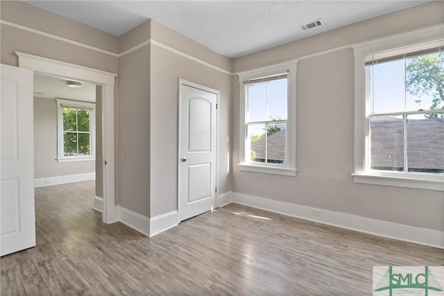 spare room with visible vents, plenty of natural light, and wood finished floors