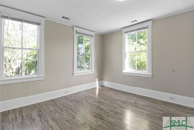 spare room with baseboards, visible vents, and wood finished floors
