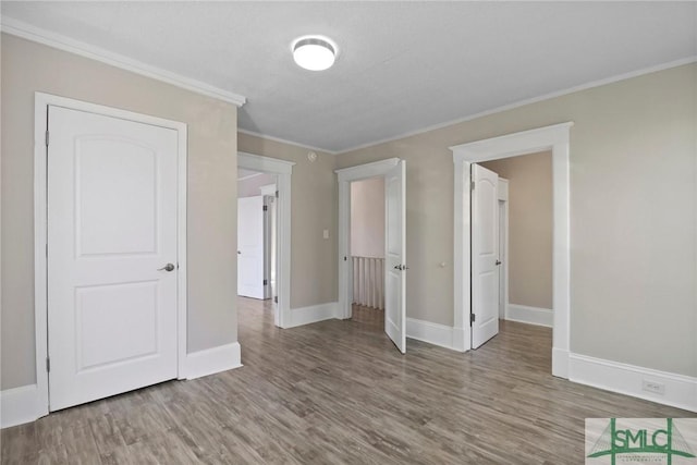 unfurnished bedroom with crown molding, baseboards, and wood finished floors