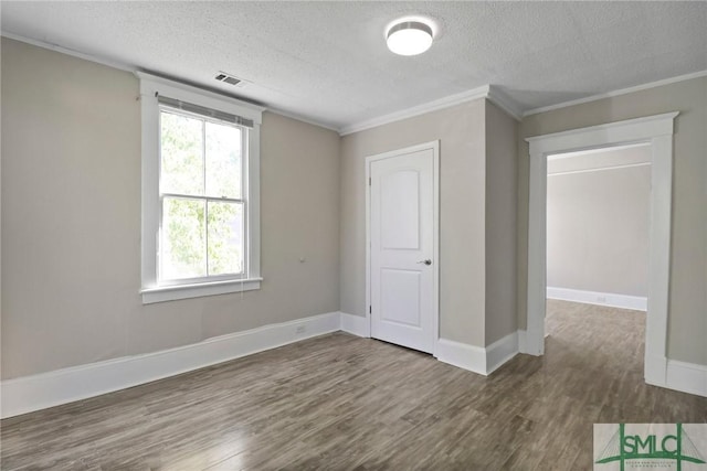 empty room with visible vents, a textured ceiling, and wood finished floors