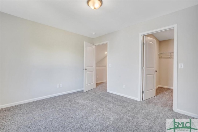 unfurnished bedroom featuring carpet flooring, baseboards, a spacious closet, and a closet