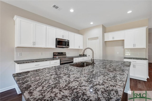 kitchen featuring visible vents, an island with sink, white cabinetry, a sink, and appliances with stainless steel finishes
