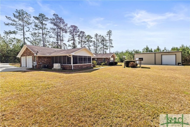 view of yard with a sunroom, driveway, and a detached garage
