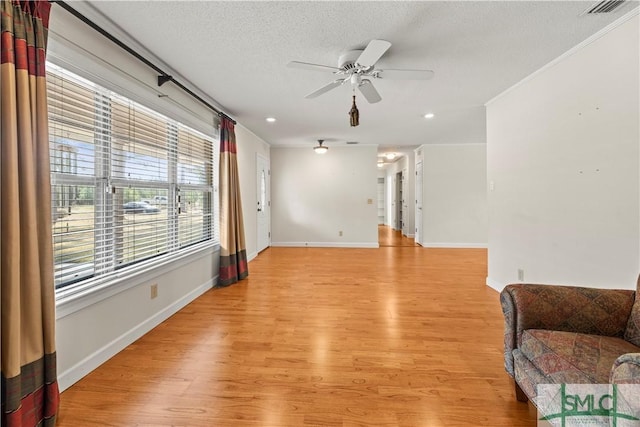 unfurnished living room featuring baseboards, ceiling fan, light wood finished floors, and a textured ceiling