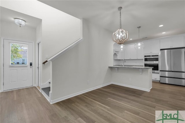 127 Lower Creek Dr, Richmond Hill, GA 31324 - kitchen with a peninsula, white cabinetry, a sink, dark wood finished floors, and stainless steel appliances