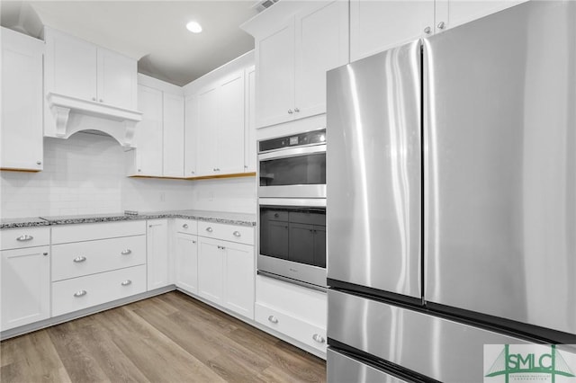 127 Lower Creek Dr, Richmond Hill, GA 31324 - kitchen featuring appliances with stainless steel finishes, white cabinets, light stone countertops, and light wood finished floors