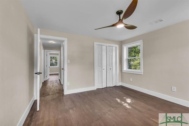 1107 E Derenne Ave, Savannah, GA 31406 - unfurnished bedroom with baseboards, multiple windows, dark wood-type flooring, and visible vents