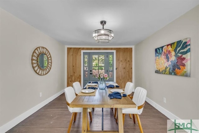 1107 E Derenne Ave, Savannah, GA 31406 - dining room with baseboards, wood walls, wood finished floors, and an inviting chandelier