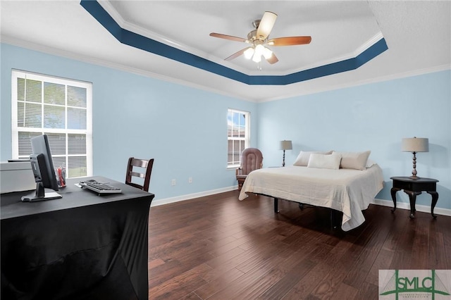 bedroom featuring ornamental molding, dark wood finished floors, and a tray ceiling