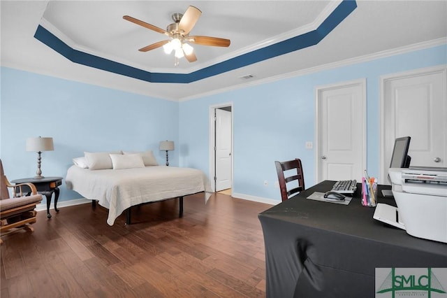 bedroom with baseboards, dark wood finished floors, crown molding, and a tray ceiling