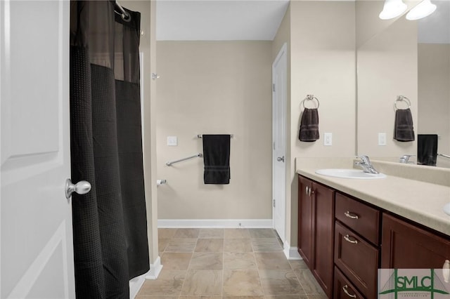 bathroom with double vanity, baseboards, curtained shower, and a sink