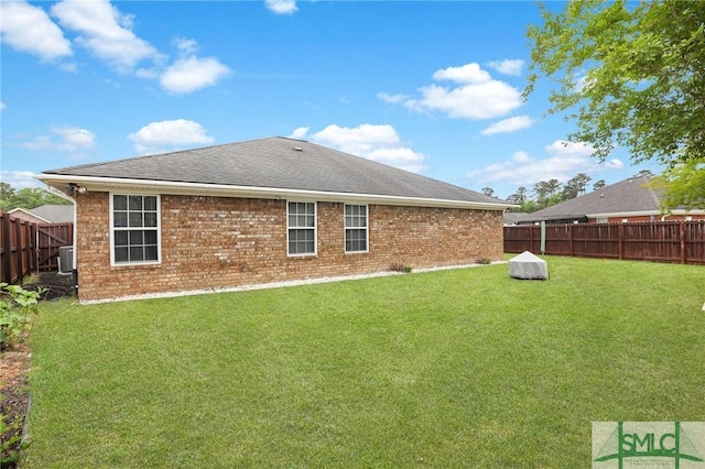 rear view of property with a fenced backyard, a yard, and brick siding