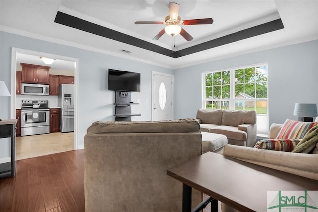 living area featuring ceiling fan, visible vents, crown molding, a raised ceiling, and dark wood-type flooring