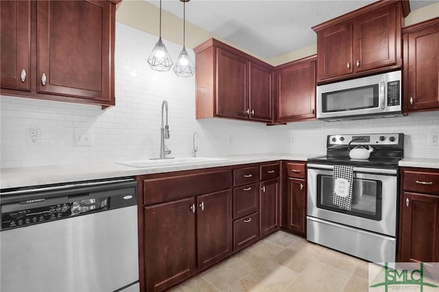 kitchen with hanging light fixtures, a sink, light countertops, stainless steel appliances, and decorative backsplash