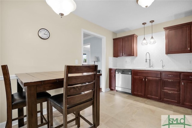 kitchen featuring stainless steel dishwasher, decorative backsplash, light countertops, a sink, and hanging light fixtures